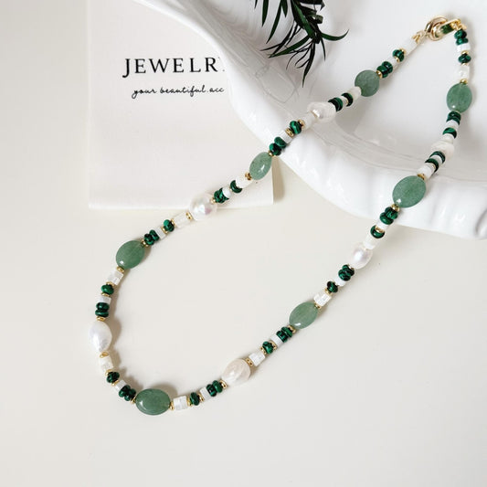Close-up of green aventurine beads, malachite accents, freshwater pearls, and gold-tone details.