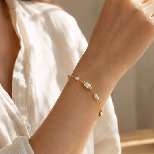 Gold freshwater pearl bracelet worn on the wrist in warm natural light