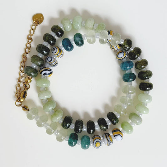 Close-up of soft green stone beads, dark green beads, and patterned accent beads.
