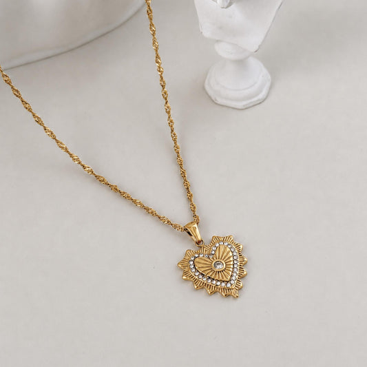 Gold Radiant Heart Pendant Necklace styled beside a white sculptural bust on a soft ivory surface