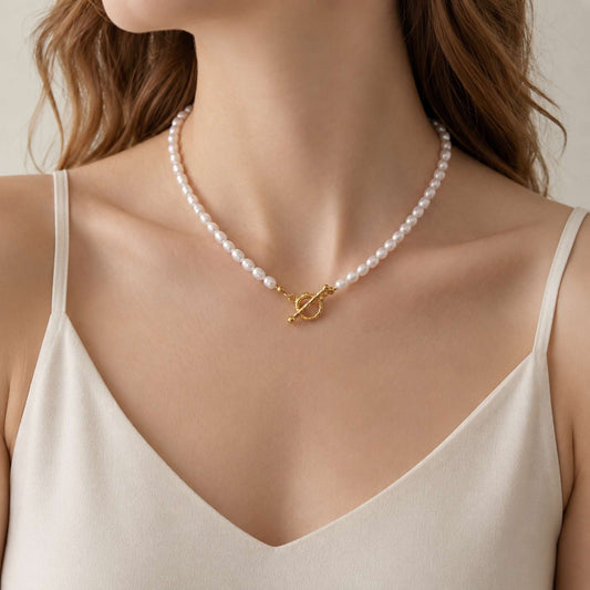 Model wearing a freshwater pearl necklace with a gold toggle clasp and white camisole.