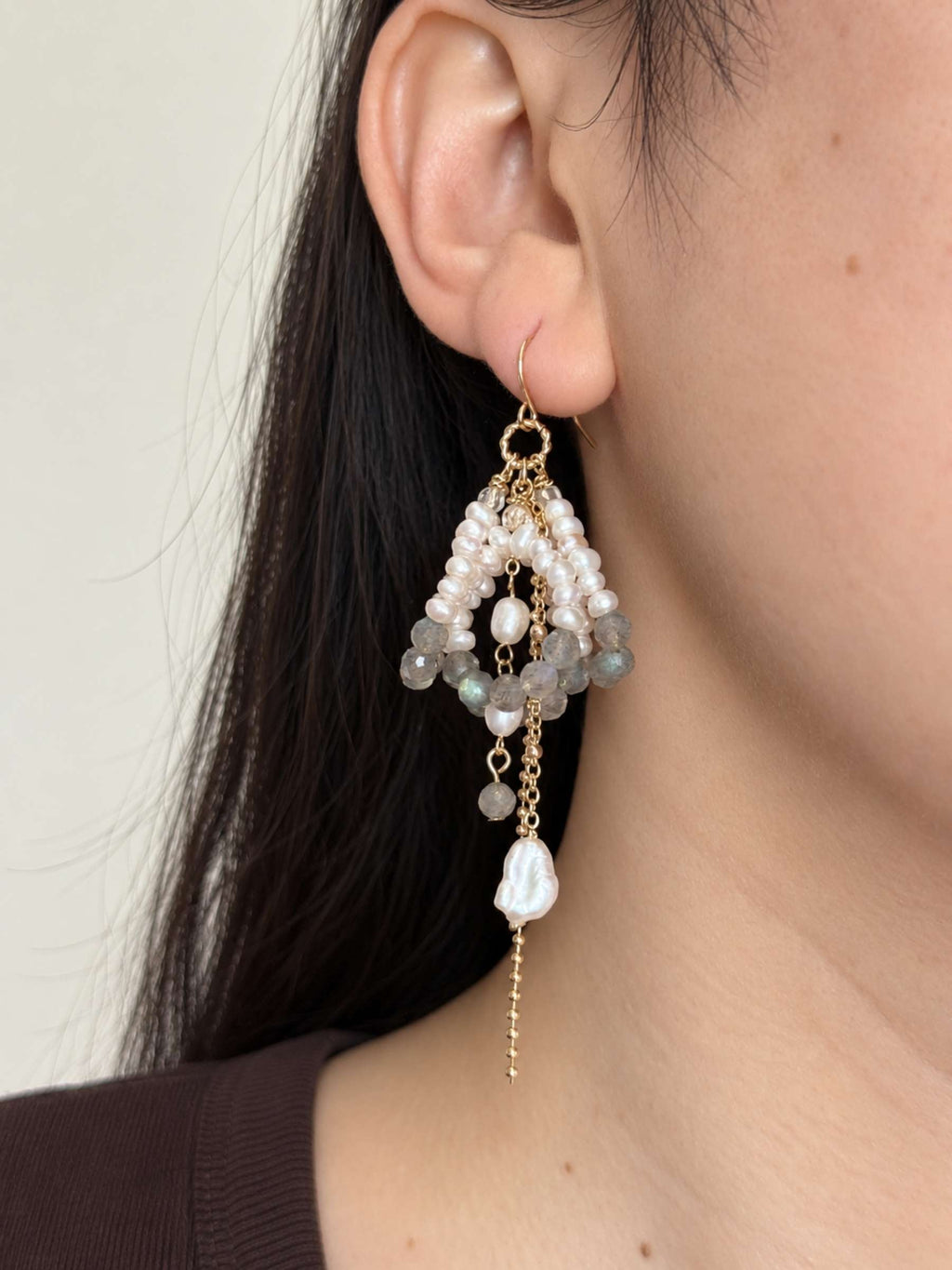 Arc labradorite and freshwater pearl statement earring worn in side profile with layered chain drops.