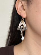 Arc labradorite and freshwater pearl statement earring worn in side profile with layered chain drops.