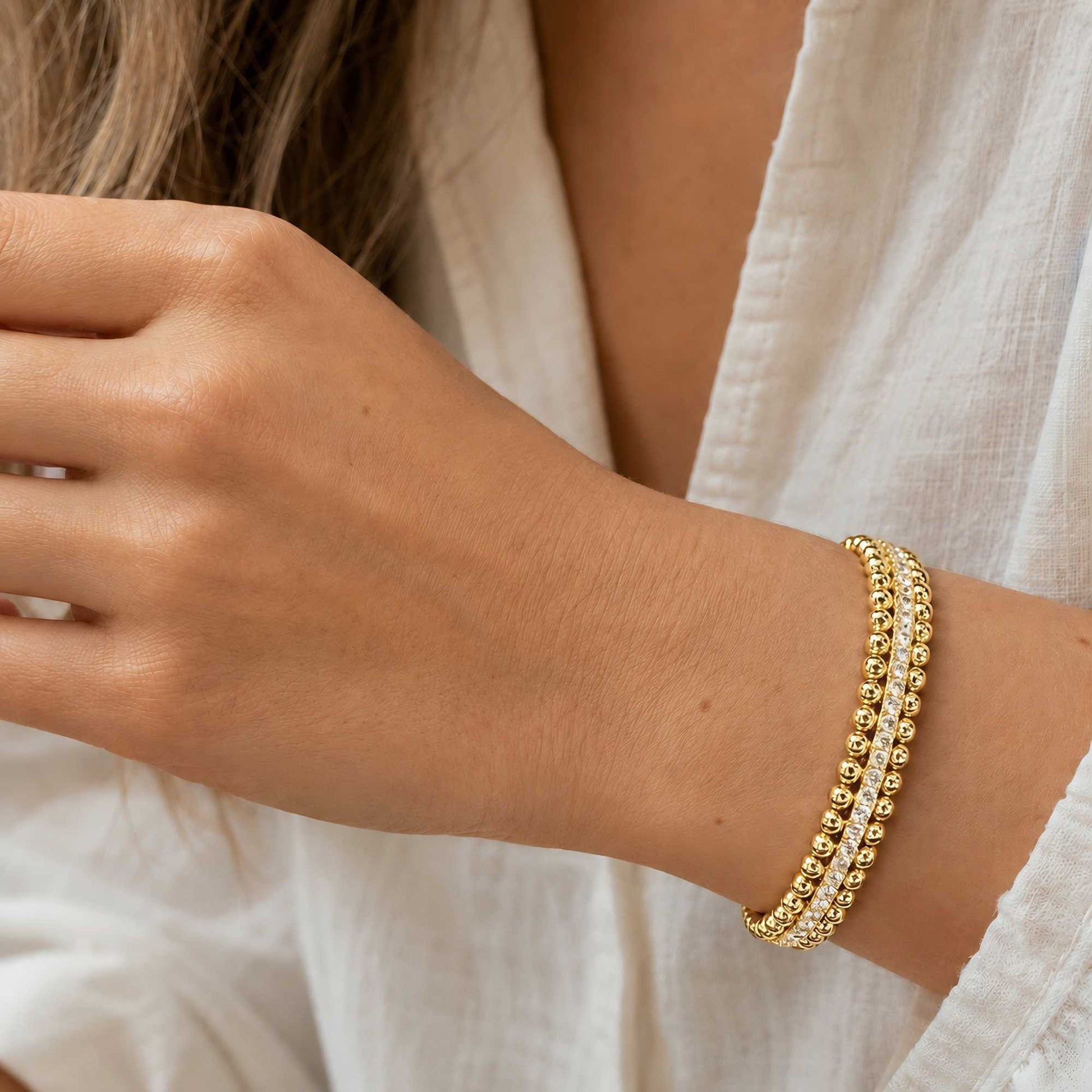 Gold-tone CZ beaded cuff bracelet worn on wrist in natural sunlight