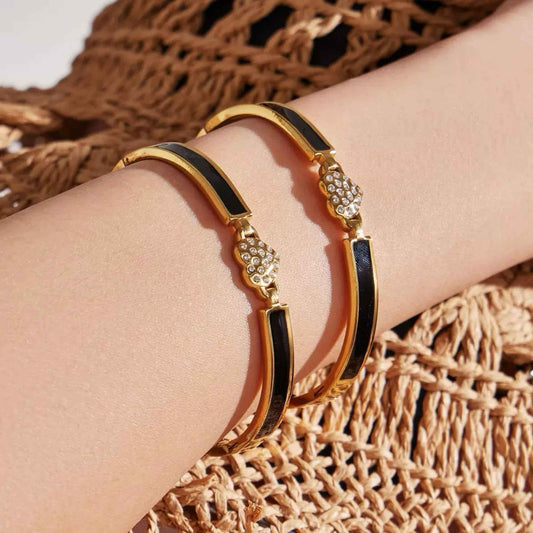 Two Blackline Heart Bangles worn on the wrist showing the structured black and gold design in natural light