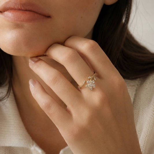 Gold floral ring styled on the hand in soft natural light.