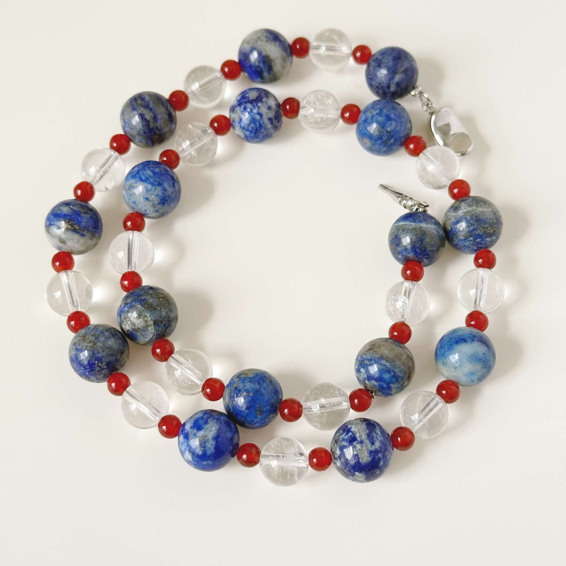 Close-up of blue stone beads, small red chalcedony beads, and clear quartz beads.