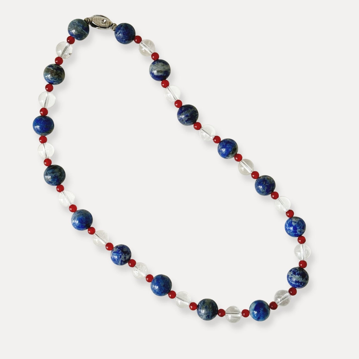Blue, red, and clear natural stone beaded necklace arranged on a light background.
