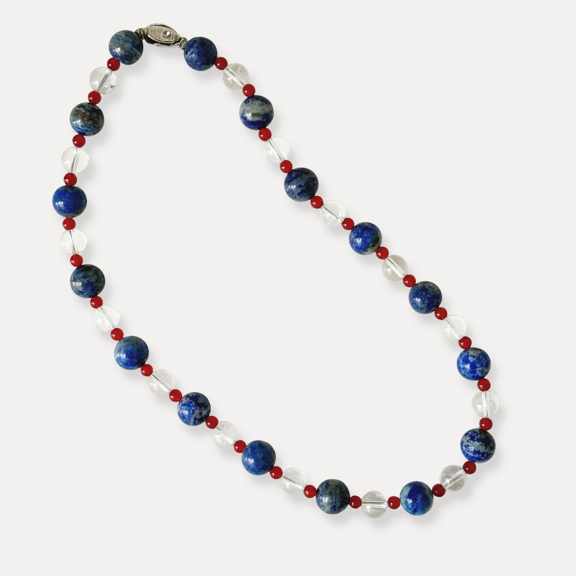 Blue, red, and clear natural stone beaded necklace arranged on a light background.