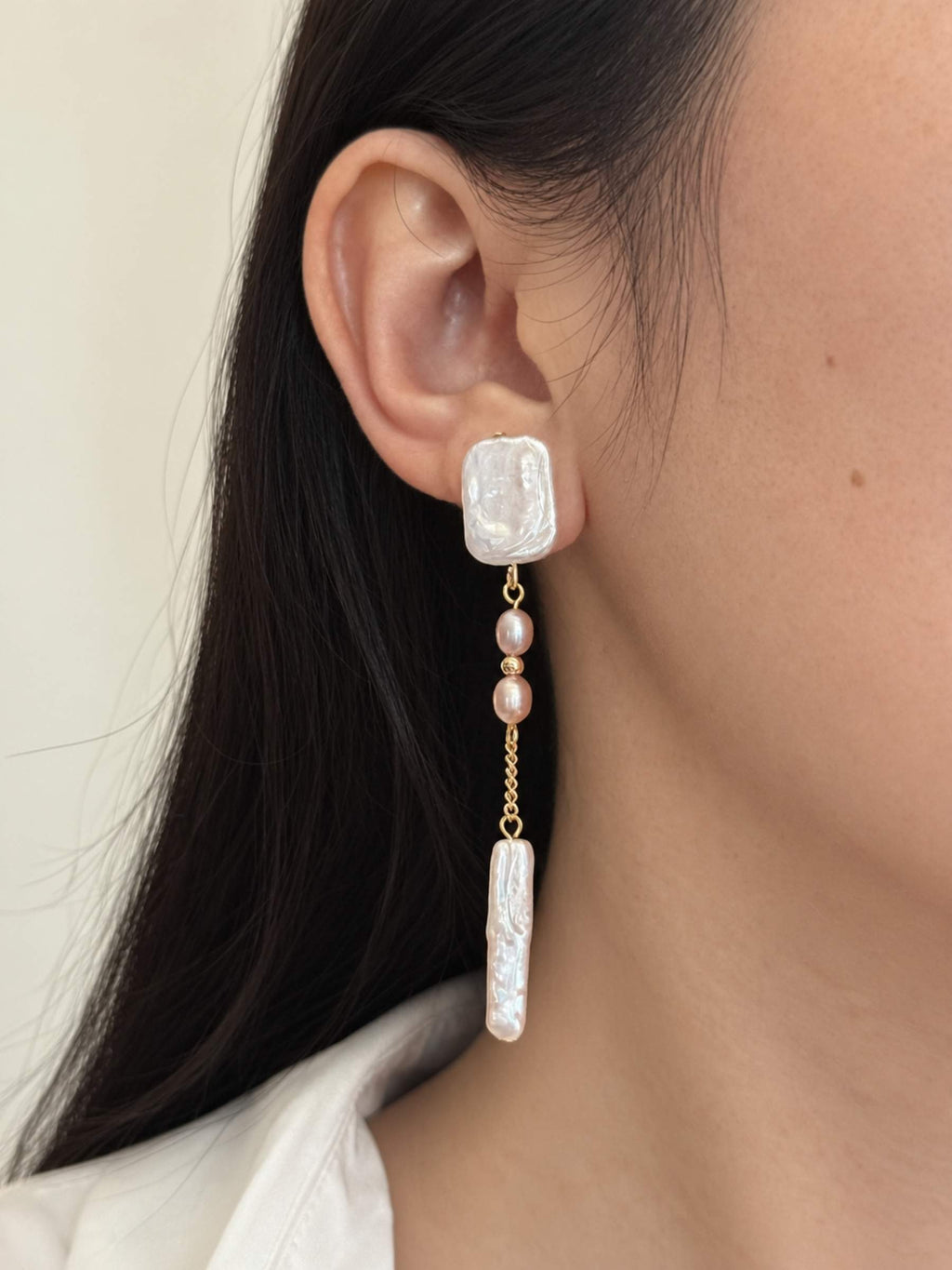 Cadence long pearl drop earring worn in side profile, showing its slender silhouette and soft pink pearl details.