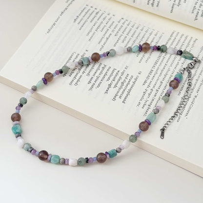 Close-up of mixed stone beads in blue, gray, purple, white, and smoky brown tones.
