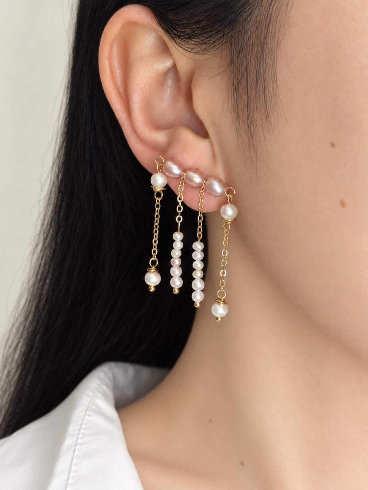 Contour freshwater pearl ear climber worn along the earlobe with four delicate pearl and chain drops.