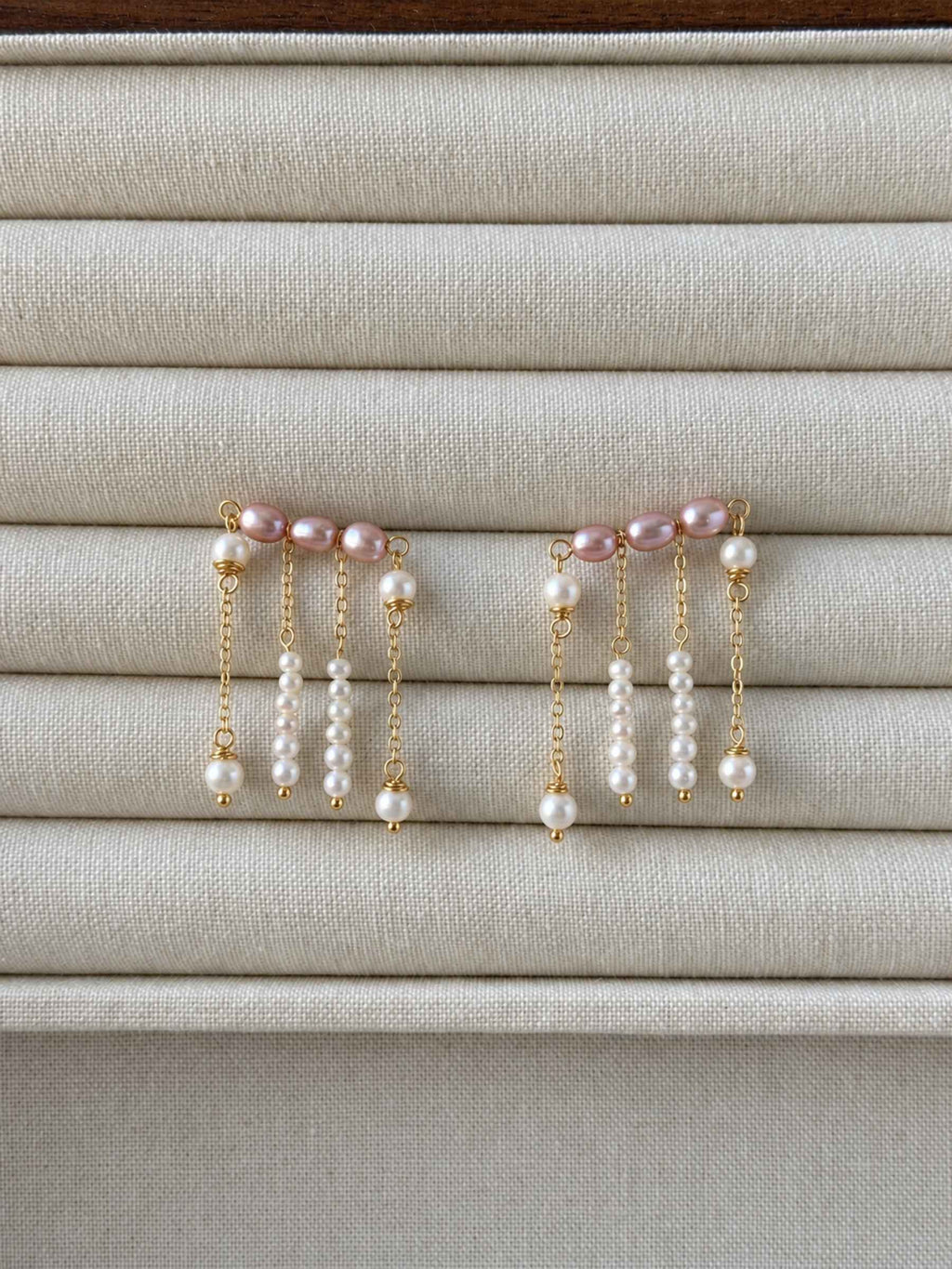 Contour pink and white freshwater pearl earrings displayed on a neutral linen jewelry tray.