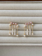Contour pink and white freshwater pearl earrings displayed on a neutral linen jewelry tray.