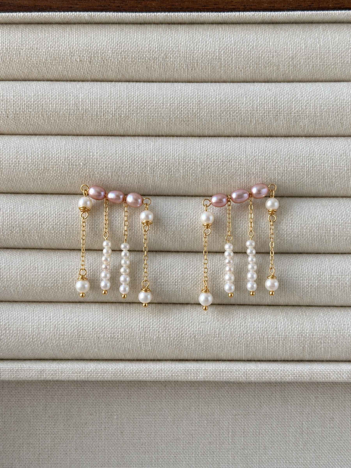 Contour pink and white freshwater pearl earrings displayed on a neutral linen jewelry tray.