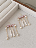 Contour pearl fringe earrings arranged on a linen tray, showing the layered chains and pearl drops.
