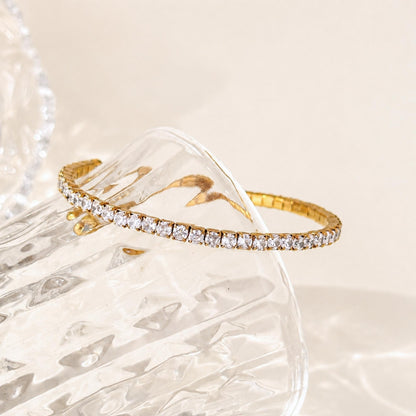 Gold Crossline CZ Bracelet styled across clear textured glass in soft natural light