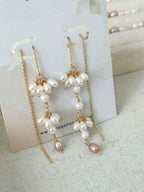 Pair of Drift freshwater pearl threader earrings displayed on a jewelry card, showing the asymmetric clustered drops.