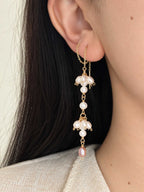 Long Drift pearl threader earring worn through the ear, showing the asymmetric pearl clusters and blush pearl drop.