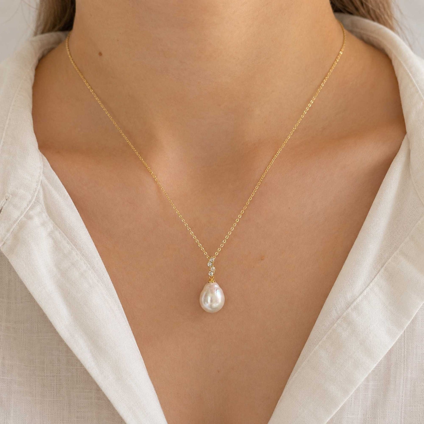 Model wearing the Elara baroque freshwater pearl pendant necklace with a light gold chain