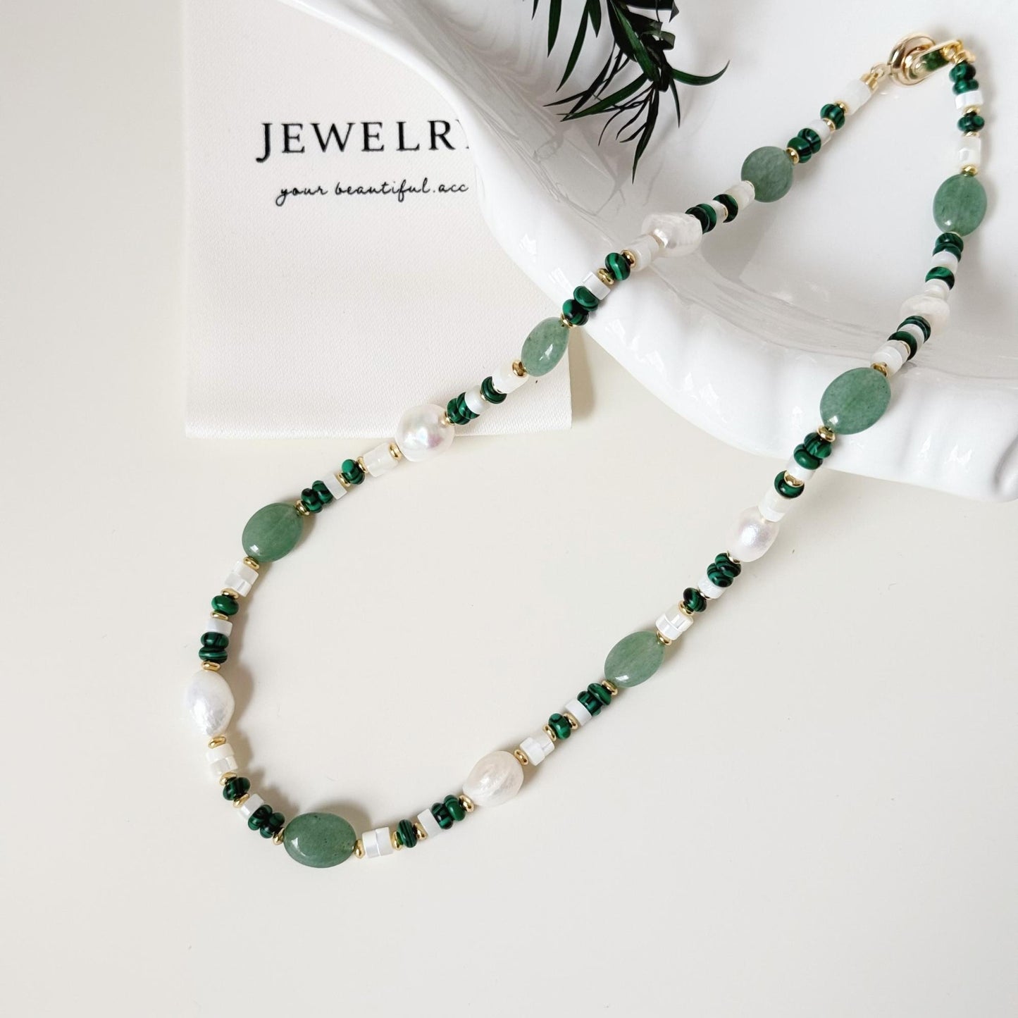 Close-up of green aventurine beads, malachite accents, freshwater pearls, and gold-tone details.