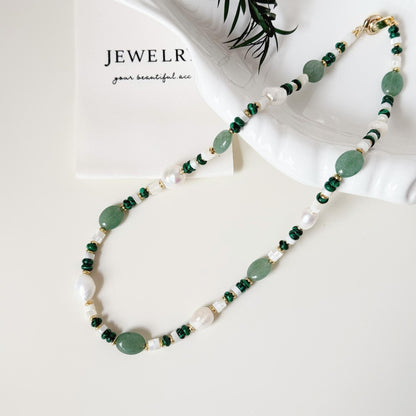 Close-up of green aventurine beads, malachite accents, freshwater pearls, and gold-tone details.
