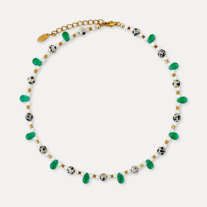 Green and white beaded necklace with speckled stones, green drop beads, and gold-tone details.