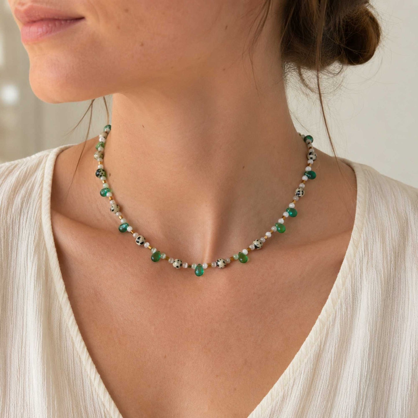 Model wearing a short green and white beaded necklace with small speckled stone details.