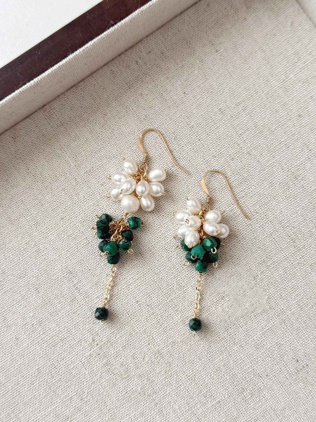 Grove natural malachite and pearl earrings arranged on a neutral linen jewelry tray.