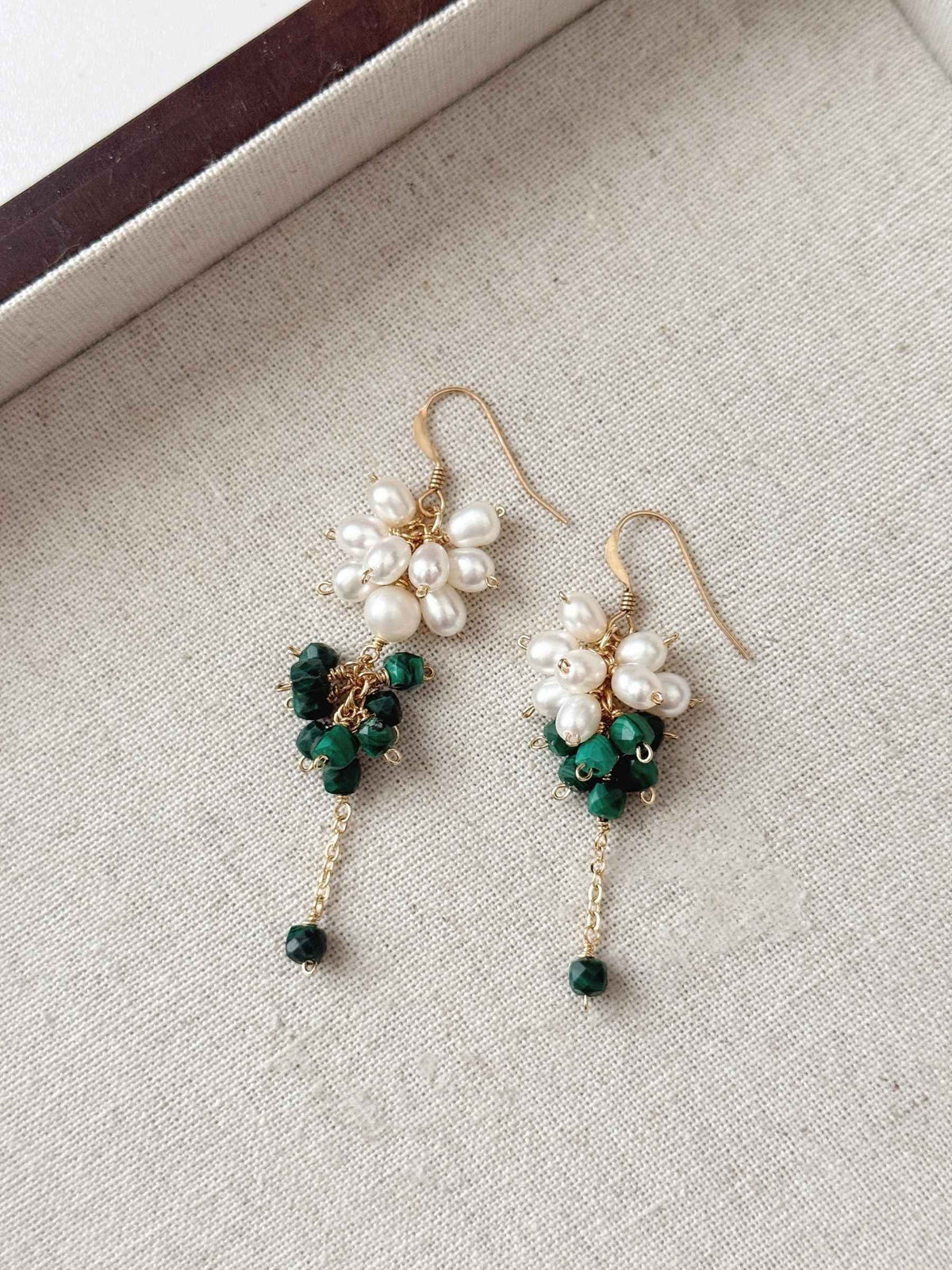 Grove natural malachite and pearl earrings arranged on a neutral linen jewelry tray.