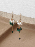 Pair of Grove malachite and freshwater pearl earrings displayed on warm neutral paper with delicate chain drops.