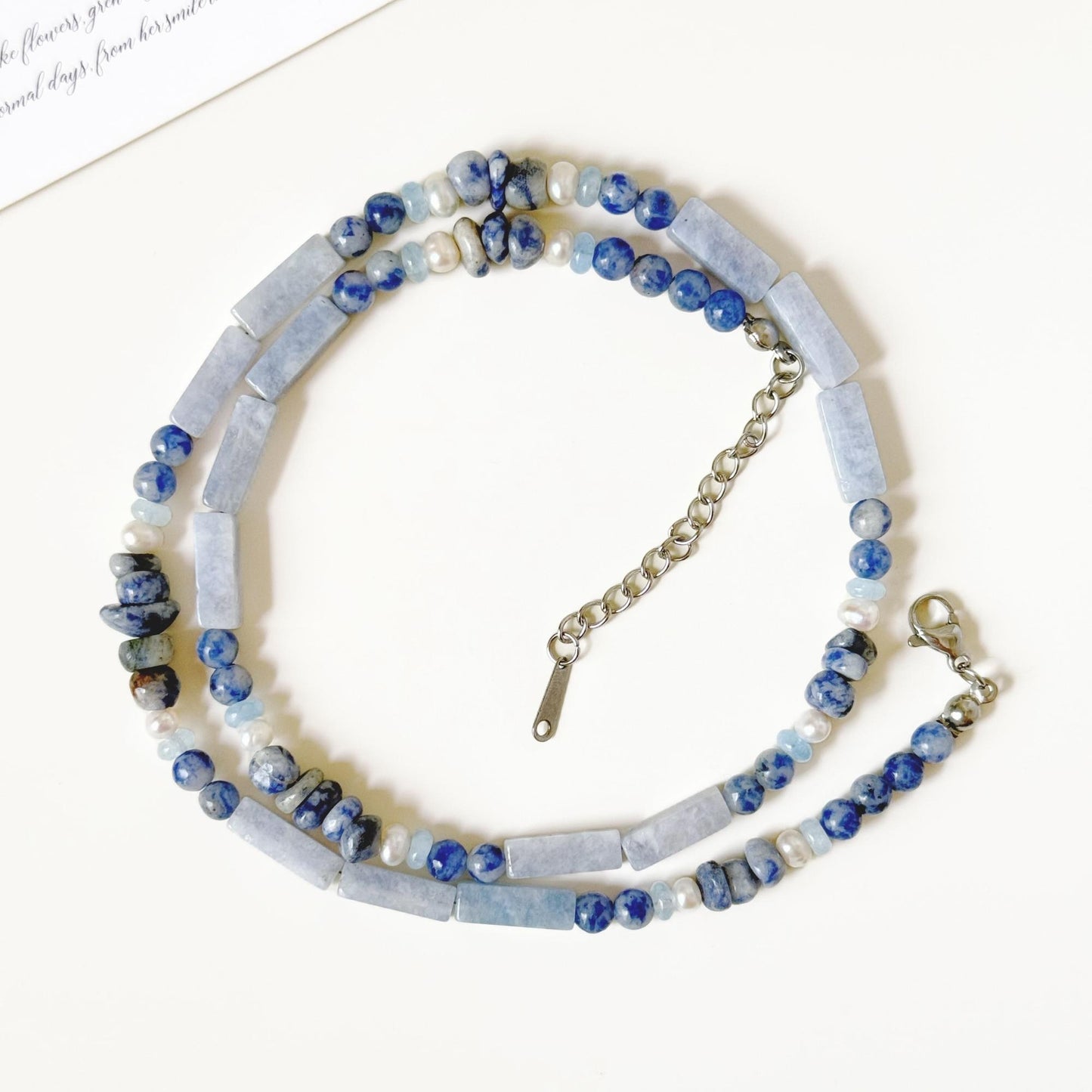 Close-up of blue-gray agate beads and small freshwater pearls with natural variation.