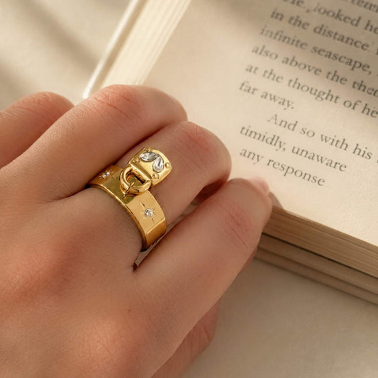 Keepsake Heart Lock Ring worn on the finger beside an open book in warm natural light