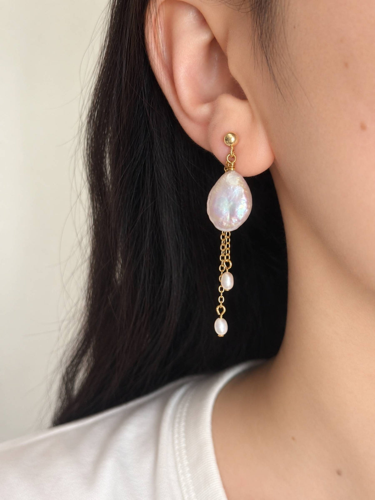 Lilt baroque pearl drop earring worn in side profile, featuring fine gold chains and small pearl accents.