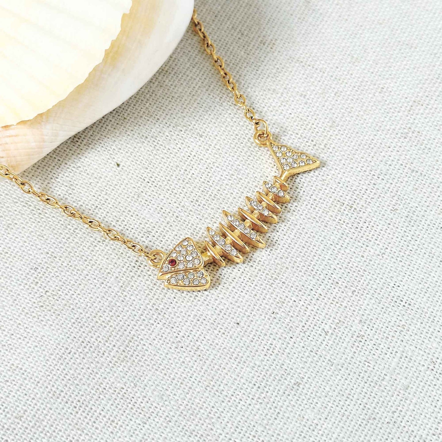 Close-up of the fishbone pendant with clear zirconia stones and a tiny red accent.