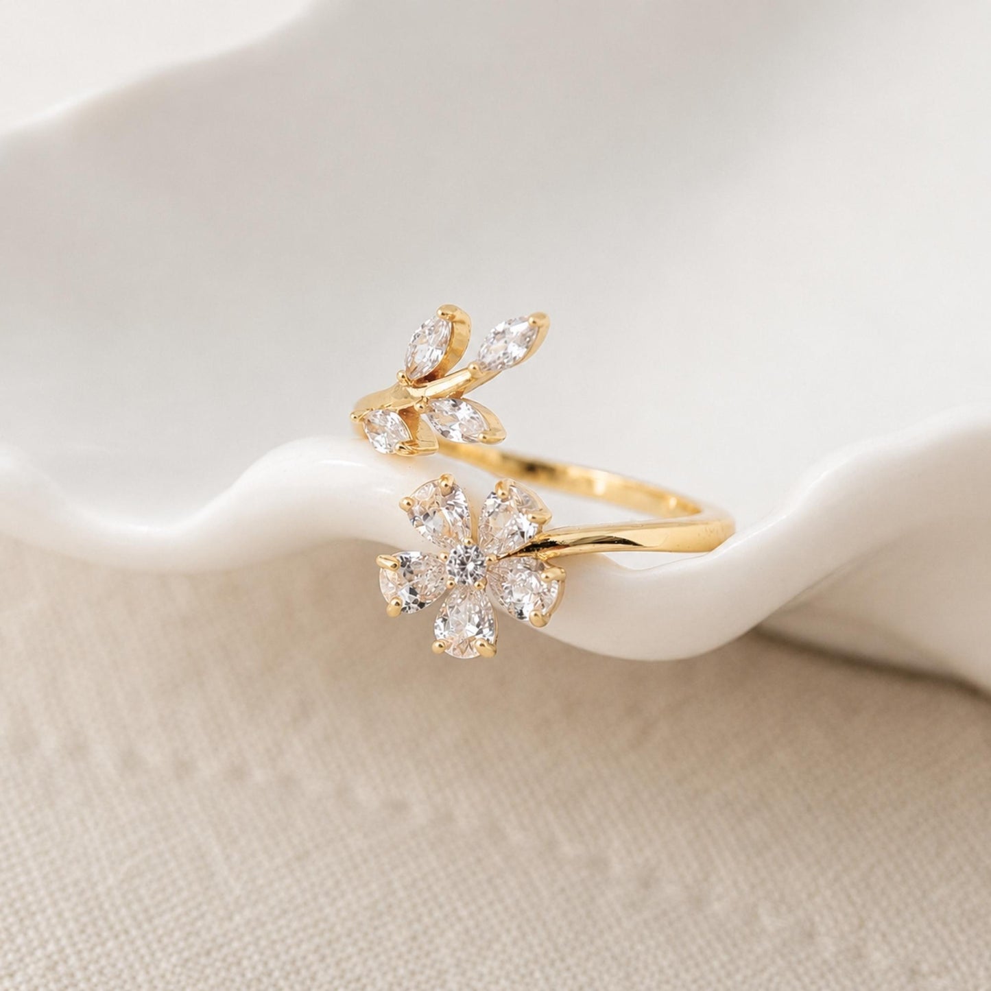 Close-up of a gold floral ring with clear zircon petals and leaf details.