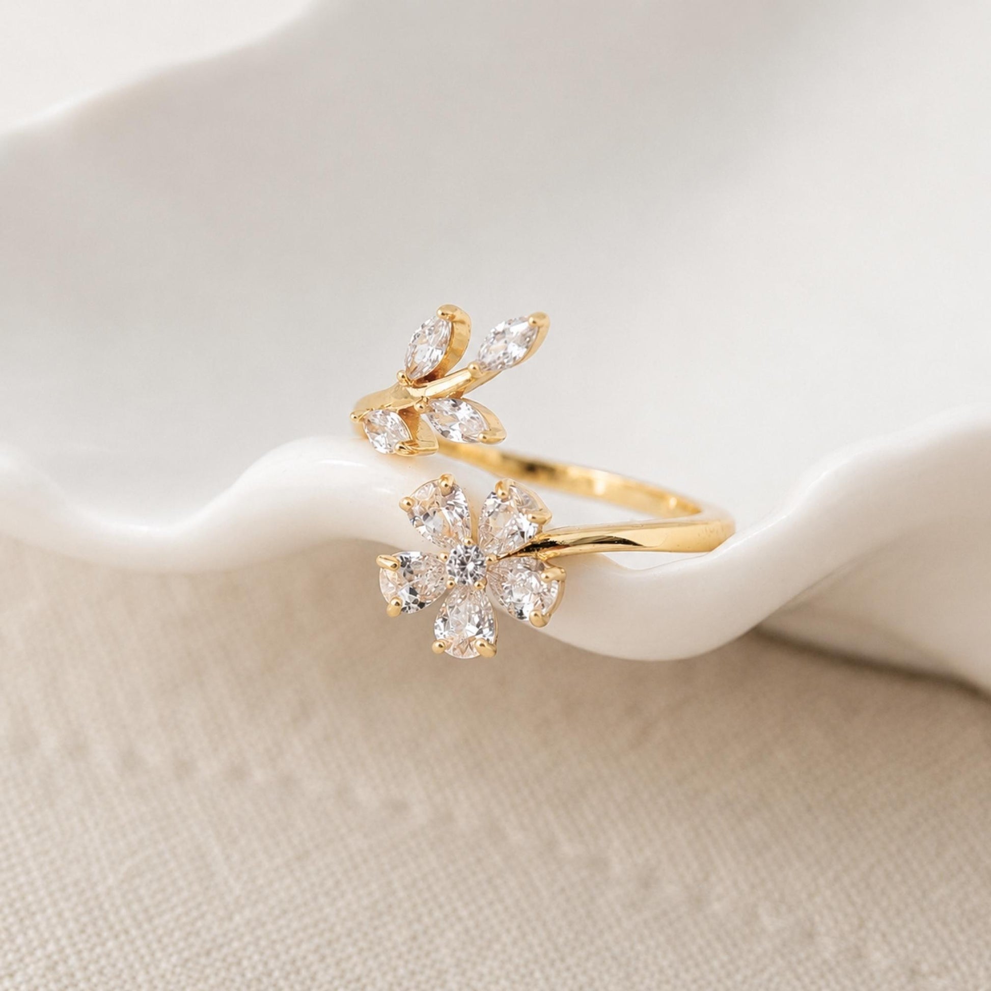 Close-up of a gold floral ring with clear zircon petals and leaf details.