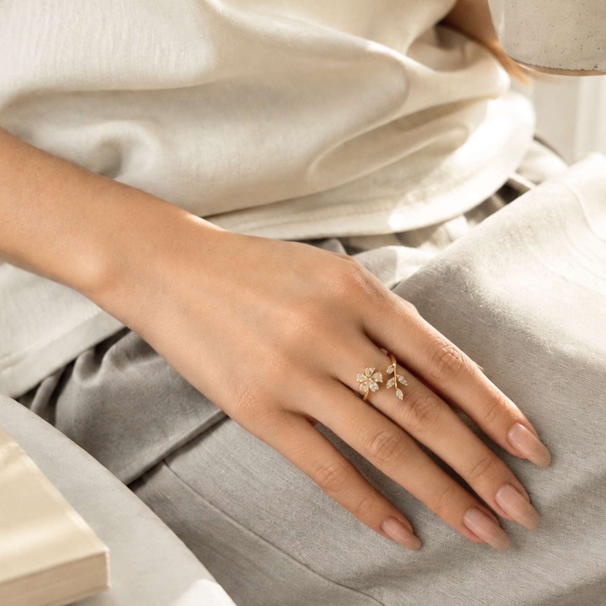 Gold flower ring styled on the hand in soft natural light.