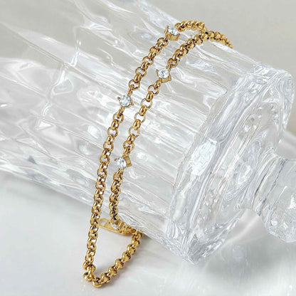 Close-up of gold chain links with small zircon stones in soft natural light.