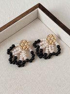 Loom pearl and black agate earrings arranged on a neutral linen jewelry tray.