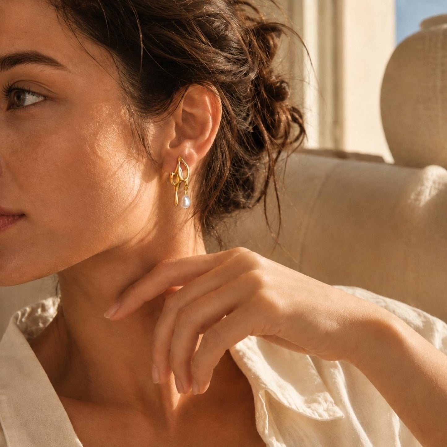 Gold pearl drop earrings styled with a soft white shirt in sunlit light