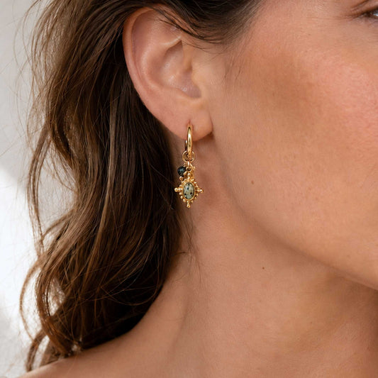 Gold natural stone charm hoop earrings worn in warm coastal light