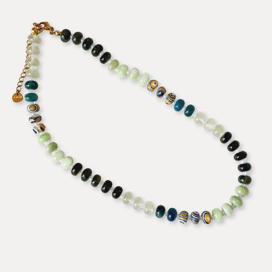 Green beaded necklace with natural stone beads and patterned accent beads on a light background.