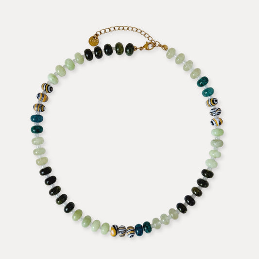 Green beaded necklace with natural stone beads and patterned accent beads on a light background.