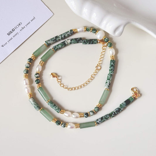 Close-up of green aventurine, freshwater pearls, and gold-plated details on a beaded necklace.