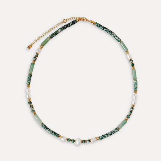 Green stone and freshwater pearl necklace with gold details arranged on a soft light background.