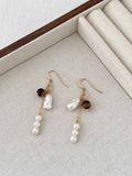 Tiger eye and freshwater pearl earrings arranged on a neutral linen jewelry tray with warm gold-filled details.