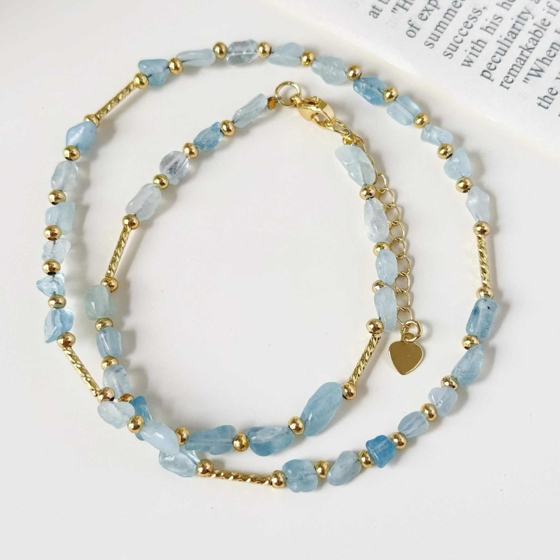 Close-up of pale blue stone beads and small gold-plated accents with natural variation.