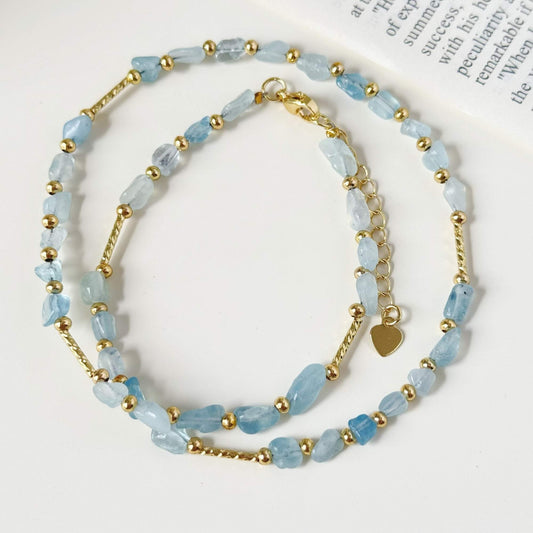 Close-up of pale blue stone beads and small gold-plated accents with natural variation.