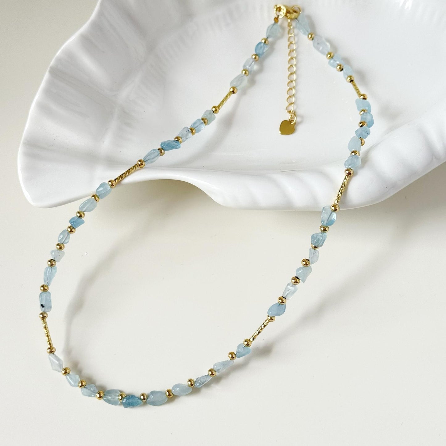Soft blue natural stone necklace styled on a white dish with gold-plated hardware.